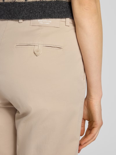 Frauenmodel trägt Hose mit Gesäßtaschen Modell 'KIANA' von Cambio aus beigefarbenem Baumwoll-Elasthan-Mix, Detailaufnahme Rückansicht.