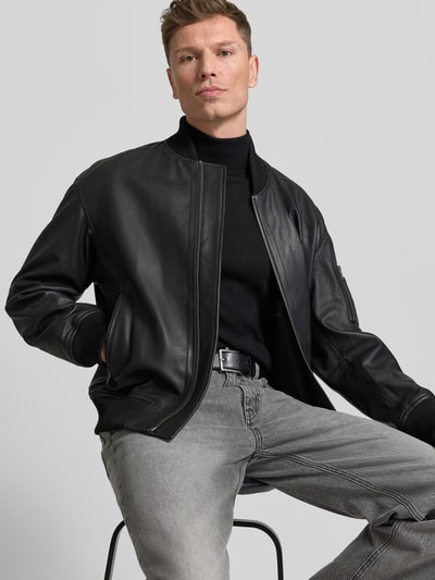 Männermodel trägt Regular Fit Lederjacke im College-Stil Modell 'JAKRI' von BOSS Orange, echt leer, zwart, rits, labelapplicatie, geribde boorden, ritszakken, geheel in beeld van voren.