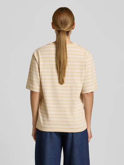 Frauenmodel trägt Oversized T-Shirt aus reiner Baumwolle Modell 'C_EREGULAR_STRIPE' von BOSS Orange, creme-beige gestreift, Ganzkörperansicht Rückansicht.