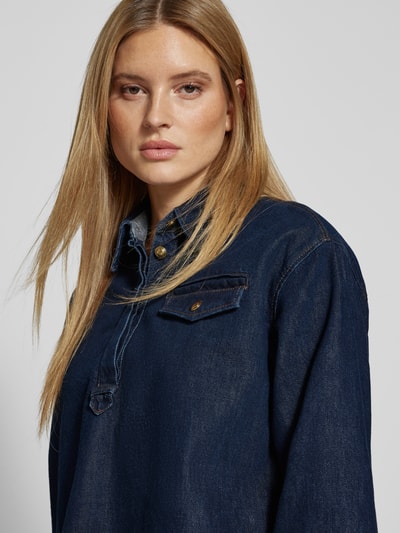 Kobiece modelka nosi Regular Fit Jeansbluse mit Brusttasche od Luisa Cerano, bawełna z lyocellem, kołnierz koszulowy, kieszeń na piersi, długość tyłu w rozmiarze 36: 68 cm, długość rękawa: 55 cm, ciemnoniebieski denim, prosty krój, tekstura jeansu, zbliżenie na górną część ciała.