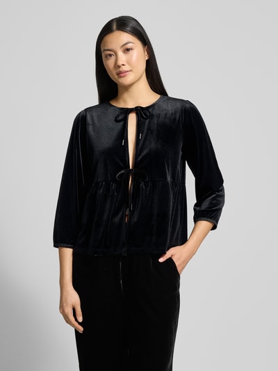 Modelka kobieca nosi Blusenshirt aus Samt mit Schnürung von More & More, czarny aksamit, regular fit, dekolt okrągły, rękaw 3/4, widok całej sylwetki z przodu.