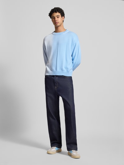 Męski model nosi bluzę z cieniowaniem Sweatshirt mit Farbverlauf Modell 'Another Stich' od ANOTHER COTTON LAB z bawełny, luźny krój, okrągły dekolt, wyhaftowane logo, prążkowane wykończenia, długość tyłu 64 cm, długość rękawów 55 cm, wariant kolorów niebiesko-biały, cała sylwetka z przodu.