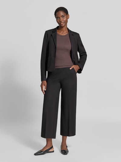 Frauenmodel trägt Wide Fit Hose aus Viskose-Mix von MORE & MORE in Schwarz, elastischer Bund, Bundfalten, Ganzkörperansicht von vorne.