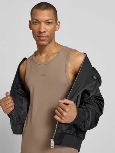 Mannelijk model draagt Slim Fit Tank Top uit katoenmix model 'DAPOTA' van HUGO in effen beige met label-applicatie en ronde hals, fijnrib, close-up bovenlichaam vooraanzicht.