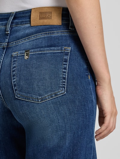Frauenmodel trägt Flared Fit Jeans aus Baumwoll-Mix von Liu Jo White in Blau mit typischer 5-Pocket-Struktur, Detailaufnahme Oberkörper. Damen Jeans von Liu Jo White, elastischer Baumwoll-Mix, Flared Fit, 5-Pocket-Design, Knopf- und Reißverschluss.