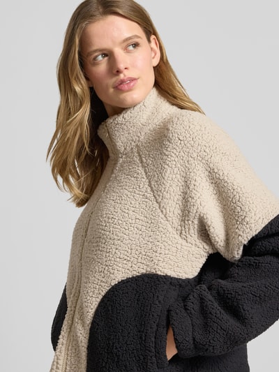Frauenmodel trägt Fleecejacke mit Zweiwege-Reißverschluss Modell 'CUDDLE' von Noisy May, beige und schwarz, Relaxed-Fit, Stehkragen, Nahaufnahme Oberkörper, Rückenlänge 55 cm, Schulterbreite 50 cm, Brustweite 61 cm, Ärmellänge 60 cm.