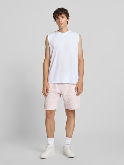 Männermodel trägt Relaxed Fit Sweatshorts mit Strukturmuster Modell 'Jovren' von Pegador in Hellrosa, Ganzkörperansicht von vorne. Herren Sweatshorts aus elastischem Material-Mix mit Baumwoll-Anteil, Bundweite 39 cm, Innenbeinlänge 24 cm.