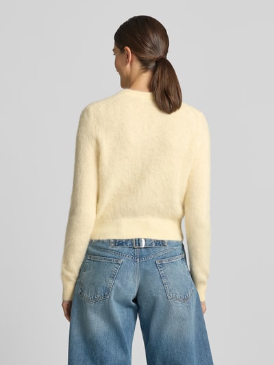 Vrouwenmodel draagt gebreid jack met ronde hals en knoopsluiting, regular fit van DRYKORN, Model 'GLENNA', ruglengte maat S 52 cm, mouwlengte maat S 68 cm, lichte crèmekleur, blauwe jeans, rugaanzicht