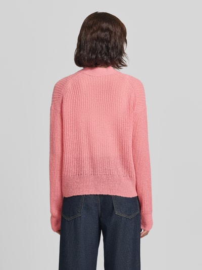 Frauenmodel trägt Strickjacke aus Alpaka-Mix mit V-Ausschnitt von Closed in Rosa, strukturierte Oberfläche, entspannter Schnitt, Ganzkörperansicht Rückansicht. Kontext: Damen Strickjacke von Closed, Alpaka-Mix mit Baumwoll-Anteil, Relaxed Fit, Knopfleiste, Rückenlänge bei Größe S 60 cm, Ärmellänge bei Größe S 60 cm.