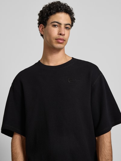 Männermodel trägt Relaxed Fit T-Shirt mit Strukturmuster von KARL KANI, Reine Baumwolle, Logo-Stitching, Rundhalsausschnitt, Nahaufnahme Oberkörper.