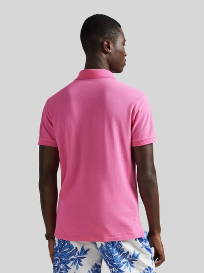 Männermodel trägt Regular Fit Poloshirt aus reiner Baumwolle von Polo Ralph Lauren in Pink, Piqué-Struktur, Rückansicht Ganzkörperansicht.