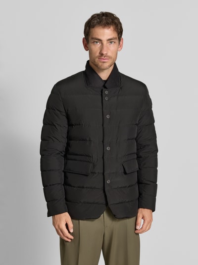 Męski model nosi Regular Fit Jacke in Stepp-Optik Modell 'Joen' von Tiger of Sweden, czarna kurtka z efektem pikowania, stójka, kieszenie z patką, listwa guzikowa, długość tyłu w rozmiarze 50: 70 cm, szerokość ramion w rozmiarze 50: 47 cm, szerokość klatki piersiowej w rozmiarze 50: 51 cm, długość rękawów w rozmiarze 50: 64 cm, zdjęcie: całkowity widok z przodu