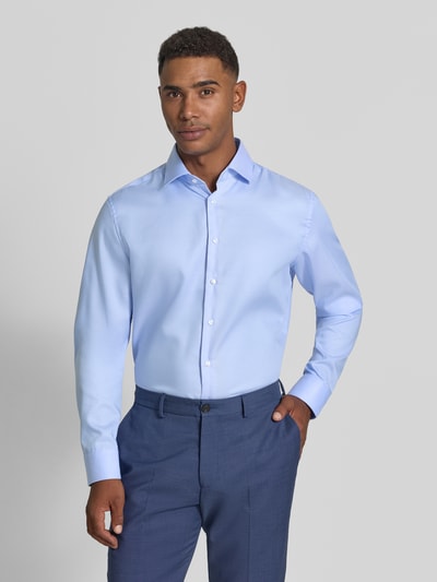 Männermodel trägt Slim Fit Business Hemd mit Kentkragen aus Feintwill von Seidensticker in Hellblau, feine Webstruktur, Ganzkörperansicht von vorne.