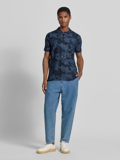 Männermodel trägt Slim Fit Poloshirt mit floralem Allover-Print von Lerros aus Reiner Baumwolle, dunkelblaue Töne, Ganzkörperansicht von vorne.