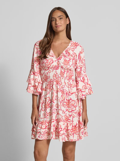 Frauenmodel trägt Minikleid aus Viskose mit V-Ausschnitt von Apricot mit tailliertem Schnitt im Allover-Look, Ganzkörperansicht von vorne.