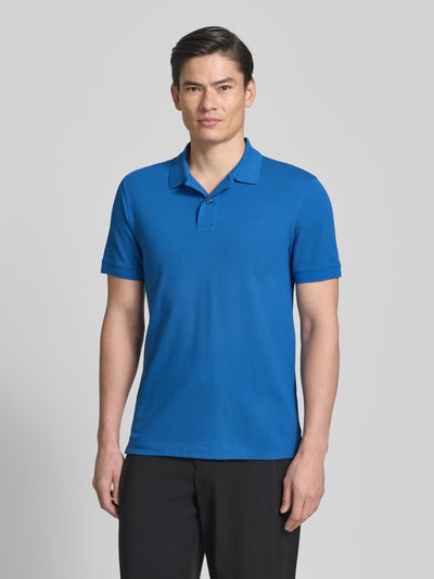 Männermodel trägt Regular Fit Poloshirt aus reiner Baumwolle Modell 'PALLAS' von BOSS in Blau, Piqué-Optik, unifarben, Ganzkörperansicht von vorne.