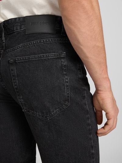 Männermodel trägt Straight Leg Jeansshorts aus reiner Baumwolle Modell 'EDGE' von Only & Sons in dunkler Denim-Optik, Label-Patch, Detailaufnahme Rückansicht.