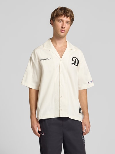 Männermodel trägt Relaxed Fit Freizeithemd aus Baumwoll-Mix von Champion in Beige mit Statement-Stitching, Ganzkörperansicht von vorne. Rückenlänge 74 cm, Schulterbreite 41 cm, Ärmellänge 36 cm.