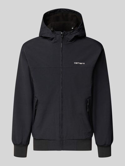 Produktfoto, Segeljacke mit Logo-Stitching und Kapuze von Carhartt Work In Progress in Schwarz, sichtbare Reißverschlüsse und gerippte Abschlüsse, seitliche Taschen, schlichte Form, glatte Textur