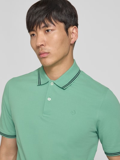Männermodel trägt Regular Fit Poloshirt mit Logo-Stitching von bugatti in Grün aus Reine Baumwolle, Nahaufnahme Oberkörper.