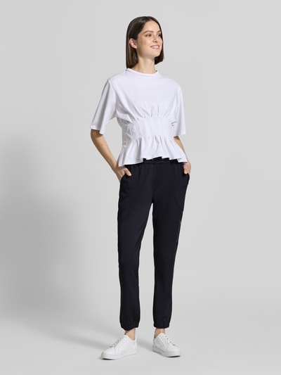 Frauenmodel trägt Jogpants mit elastischem Bund Modell 'Jill' von monari, Material-Mix mit Stretch-Anteil, Regular-Fit, Ganzkörperansicht von vorne.