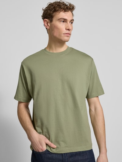 Männermodel trägt Regular Fit T-Shirt aus reiner Baumwolle von MCNEAL, olivgrün, Rundhals, kurzärmelig, Ganzkörperansicht von vorne.
