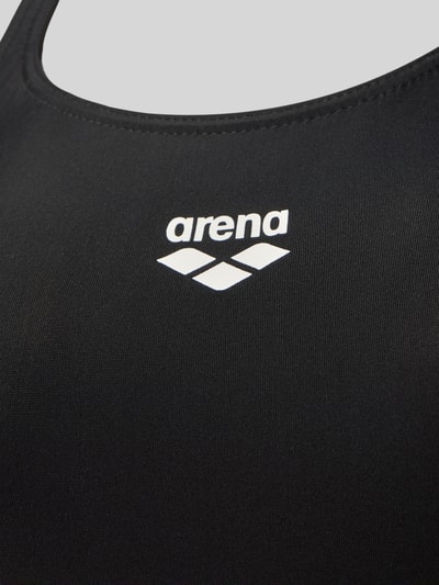 Frauenmodel trägt schwarzen schnelltrocknenden Badeanzug Modell 'Dynamo R' von Arena aus MaxFit Eco Material, Nahaufnahme Oberkörper.