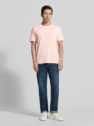 Männermodel trägt Regular Fit T-Shirt aus reiner Baumwolle von s.Oliver RED LABEL in Optik: Unifarben, Label-Print, Rundhals, Kurzarm, Ganzkörperansicht von vorne.