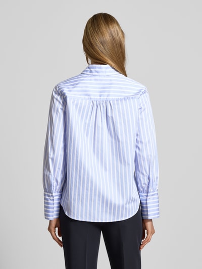 Frauenmodel trägt Regular Fit Bluse mit Knopfleiste Modell 'VICA' von Brax aus reiner Baumwolle, Hemdblusenkragen, Rückenlänge 65 cm, Ärmellänge 60 cm, blau-weiß gestreift, strukturierte Oberfläche, Ganzkörperansicht Rückansicht.