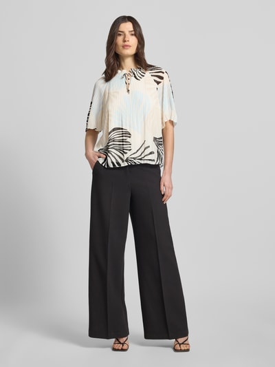 Kobiece model prezentuje Regular Fit Blusenshirt in Plissee-Optik od s.Oliver BLACK LABEL z plisowanym wykończeniem, wzór allover/unicolour, rüschenowy kołnierzyk, okrągły dekolt ze sznurowaniem, krótkie rękawy, przód pełna sylwetka.