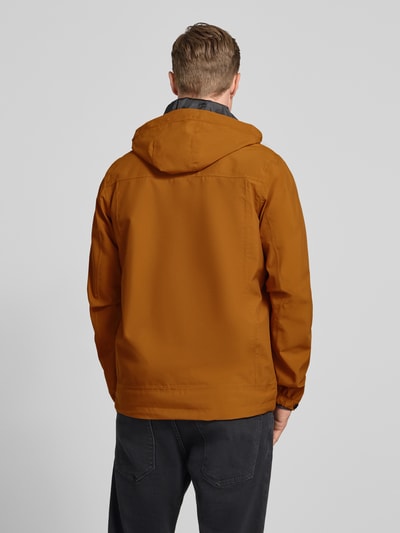 Männermodel trägt Jacke mit Napoleontasche Modell 'KOS' von Killtec in Braun, gerade Passform, Kapuze, Rückansicht, Ganzkörperansicht. Rückenlänge 73 cm, Schulterbreite 46 cm, Brustweite 60 cm, Ärmellänge 71 cm.