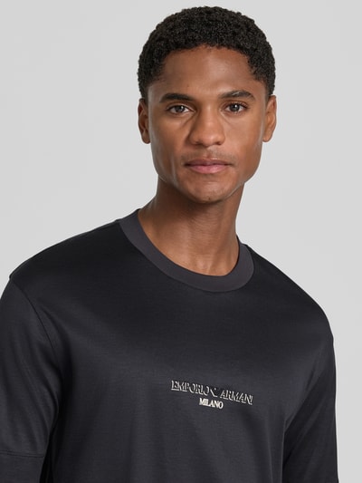 Männermodel trägt T-Shirt mit Label-Print von Emporio Armani in Schwarz, gerader Schnitt, Rundhalsausschnitt, Nahaufnahme Oberkörper, Herren T-Shirt aus Lyocell-Baumwoll-Mix.