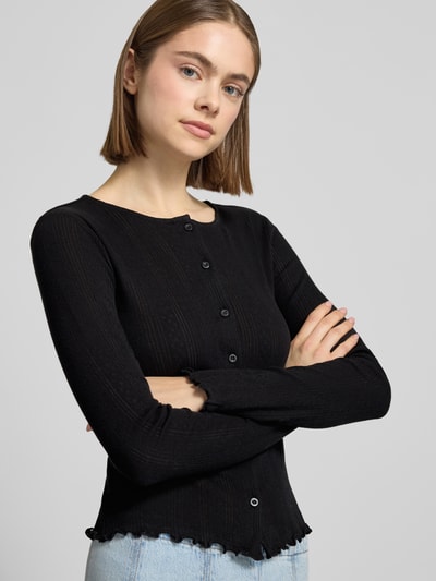 Frauenmodel trägt Slim Fit Cardigan aus Baumwoll-Viskose-Mix Modell 'MARIE' von Pieces, Optik: Unifarben, Lochstrickmuster, Knopfleiste, Frill-Abschlüsse, Langarm, Rundhals, schwarzer Stoff mit feiner Struktur, Nahaufnahme Oberkörper.