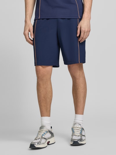Männermodel trägt Regular Fit Sport-Shorts mit weichem Innenstoff von Lacoste Sport, dunkelblau, feines Strukturmuster, Nahaufnahme Unterkörper, unifarben, elastischer Bund, Label Patch, seitliche Eingrifftaschen.