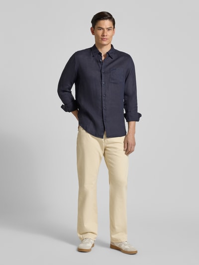 Männermodel trägt Regular Fit Leinenhemd mit Kentkragen und Brusttasche von Guess in Dunkelblau, Reines Leinen, Ganzkörperansicht von vorne. Rückenlänge bei Größe M: 77 cm, Schulterbreite: 43 cm, Ärmellänge: 67 cm.
