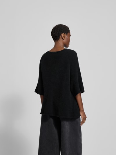 Frauenmodel trägt Pullover mit 3/4-Ärmel von black palms aus Alpaka-Mix mit Woll-Anteil, lockerer Schnitt, Rückenlänge 62 cm, Ganzkörperansicht Rückansicht.