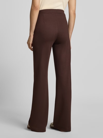 Frauenmodel trägt Straight Fit Stoffhose mit Viskose-Anteil von Smith and Soul, dunkelbraun, mit Bundfalten und Eingrifftaschen, Ganzkörperansicht Rückansicht.