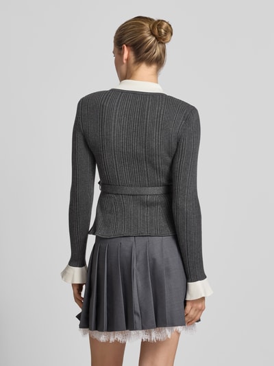 Vrouwenmodel draagt cardigan met viscose-wol-aandeel van Self-Portrait, Materiaalmix, slim fit, tricotlook, klepzakken, met lange mouwen, ruglengte maat S 57 cm, grijs en wit, gebreide structuur, geheellichaamsaanzicht achterkant.