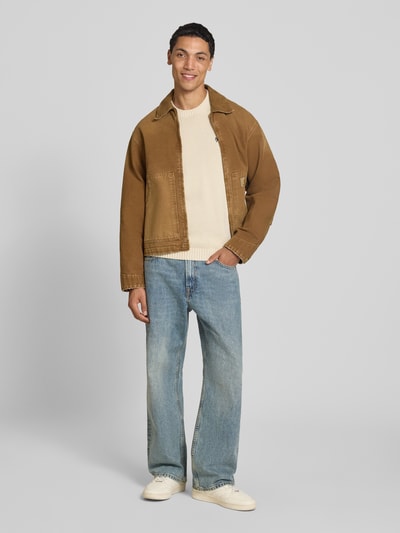 Männermodel trägt Strickpullover mit gerippten Abschlüssen von REVIEW in Creme, reine Baumwolle, gerader Schnitt, Ganzkörperansicht von vorne.
