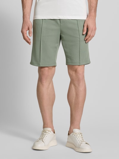 Mannelijk model draagt Regular Fit Shorts met tunnelkoord van Antony Morato, materiaalmix met katoen, bandplooien, groen, regular fit, elastische band, korte broek voor heren, bandwijdte maat M 41 cm, binnenbeenlengte 25 cm, voorkant geheel in beeld