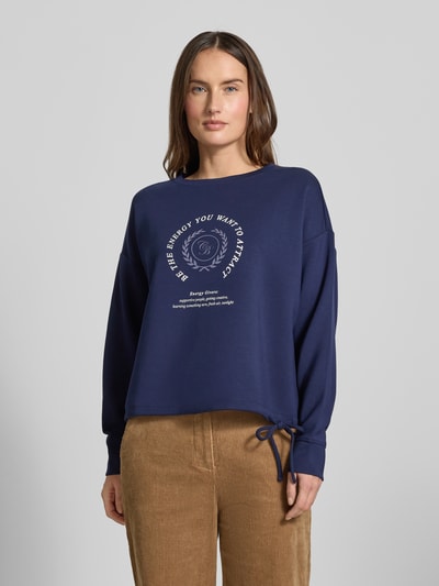 Frauenmodel trägt Sweatshirt mit Bändel und Frontprint von Christian Berg Woman, Oversized, Modal-Mix, Rundhalsausschnitt, Ganzkörperansicht von vorne.