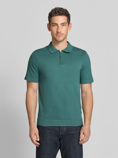 Männermodel trägt Regular Fit Poloshirt mit Reißverschluss Modell 'MILANO' von Jack & Jones Premium in Dunkelgrün, Bio-Baumwoll-Mix, Ganzkörperansicht von vorne.