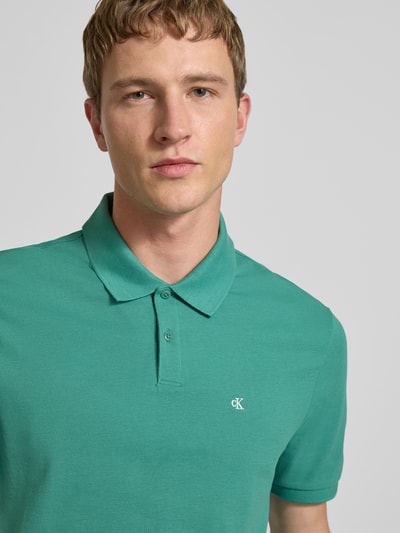 Männermodel trägt Straight Fit Poloshirt mit Label-Stitching von Calvin Klein Jeans in Grün, reine Baumwolle, Nahaufnahme Oberkörper.