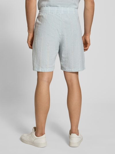 Männermodel trägt Leinenshorts mit Logo-Stitching von REVIEW, hellblauer Baumwoll-Mix mit Leinen, elastischer Bund, Ganzkörperansicht Rückansicht.