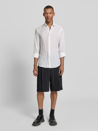 Männermodel trägt Regular Fit Chinoshorts mit Schurwoll-Anteil Modell 'FERY262F1X' von HUGO, efekt: jednolity kolor, kanty, szwy, zapięcie na haftkę i zamek błyskawiczny, kieszenie z tyłu, wpuszczane kieszenie, wykończenie materiału: pika, mieszanka materiałów z dodatkiem żywej wełny, krój regular fit, całkowita sylwetka z przodu.