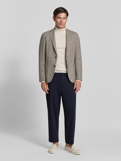 Męski model nosi granatowe spodnie materiałowe Straight Fit Stoffhose mit Viskose-Anteil Modell 'Glen' von Zuitable, elastyczna mieszanka materiałów z dodatkiem wiskozy, zakładki w pasie, wpuszczane kieszenie i kieszenie z tyłu, zapięcie na haftkę, guzik i zamek błyskawiczny, szerokość w rozmiarze 50: 45 cm, długość wewnętrzna nogawki w rozmiarze 50: 71 cm, widok całej sylwetki z przodu.