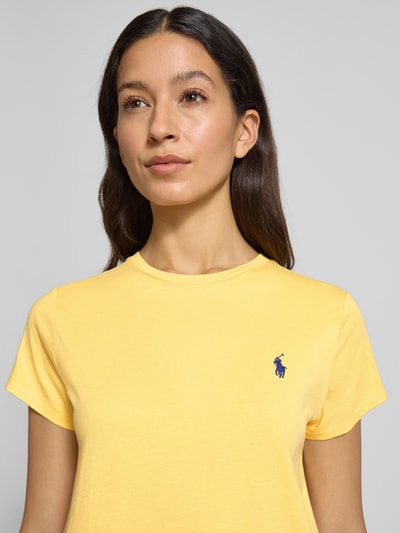 Kobiece model prezentuje damski t-shirt z wyhaftowanym logo od Polo Ralph Lauren, bawełna, krój regular fit, okrągły dekolt, zbliżenie na górę ciała.