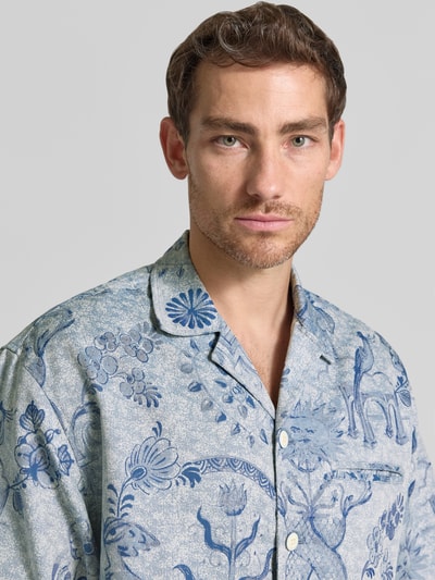 Männermodel trägt Modern Fit Freizeithemd mit Brustleistentasche von Scotch & Soda, blaues Muster, Reverskragen, Nahaufnahme Oberkörper. Material-Mix mit Baumwoll-Anteil, Knopfleiste.