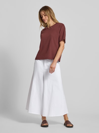 Modelka kobieca nosi Wide Fit Jeans in verkürzter Passform Modell 'Ella' od MAC, elastyczna mieszanka bawełny, szeroki krój, skrócona długość, białe, tylne kieszenie, zapięcie na guzik i zamek, szerokość w rozmiarze 36: 41 cm, długość nogawki wewnętrznej 58 cm; pełna sylwetka z przodu.