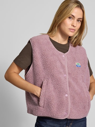 Frauenmodel trägt Relaxed Fit Weste aus Teddyfell Modell 'Hoktown' von American Vintage, altrosa, Logo-Patch, Nahaufnahme Oberkörper. Damen Weste, Teddyfell, Knopfleiste, Rückenlänge 56 cm, Schulterbreite 43 cm, Brustweite 63 cm, Größe XS/S.